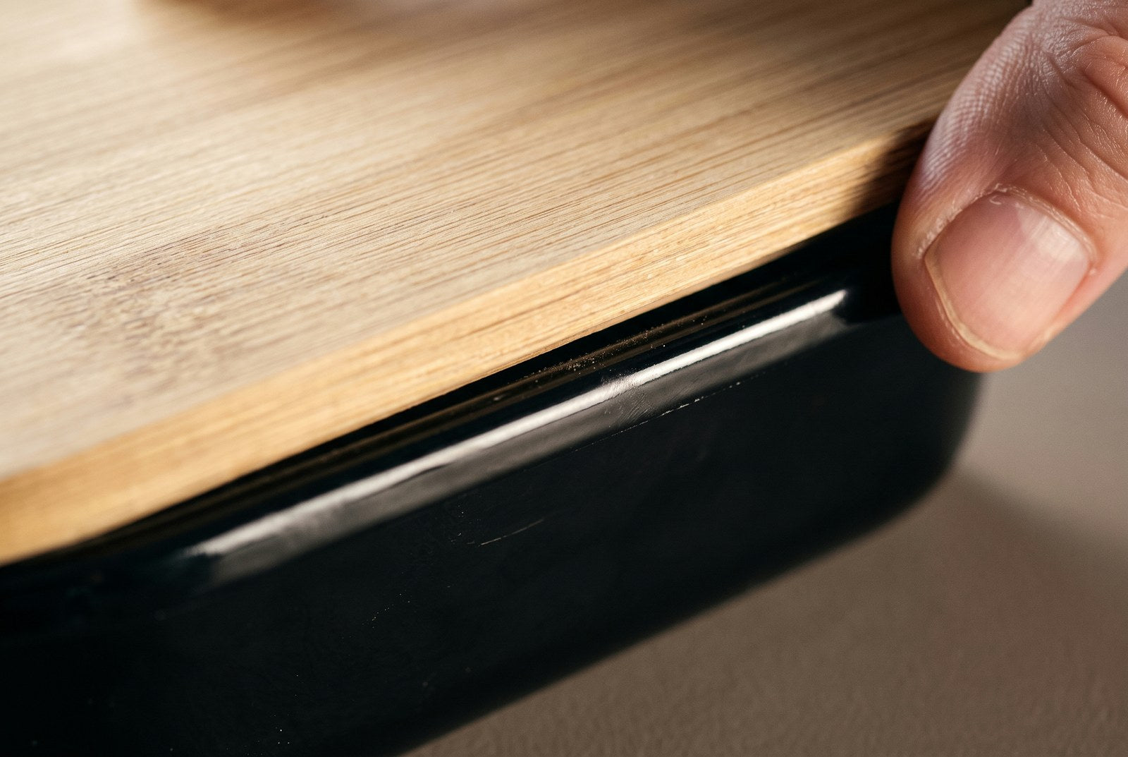 Hands running a thumb along the join between powder-coated steel and bamboo
